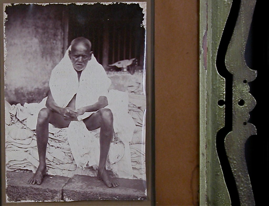 A vintage photographic image in its original frame of the aged towel vendor at the steps of the Ganges. 

 