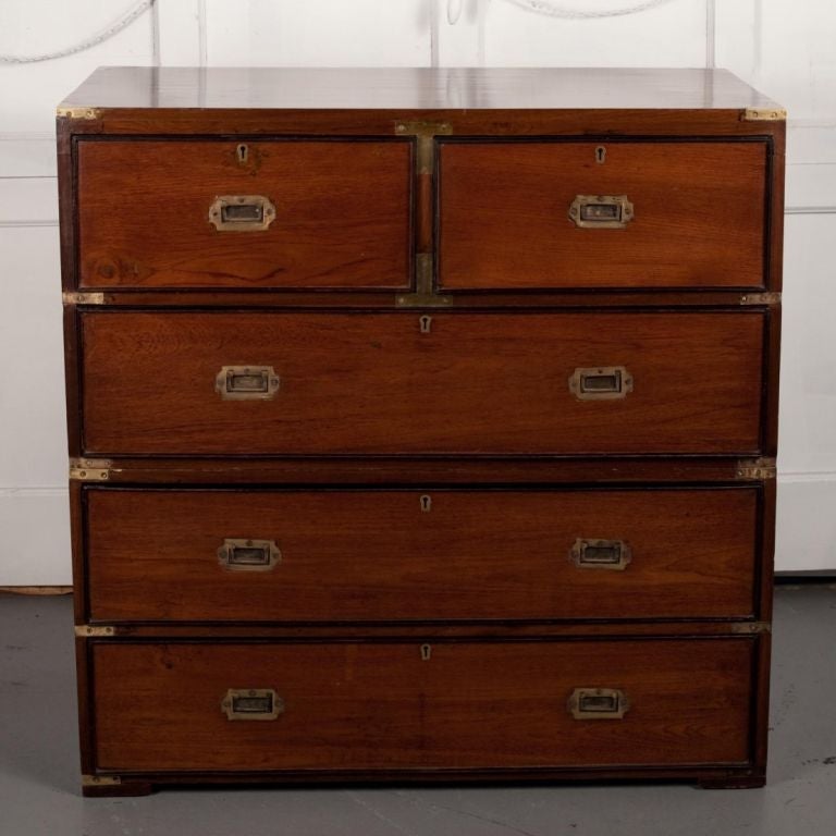 Anglo-Indian British campaign chest of drawers in teak with black detailing around drawers. Inset brass handles on drawers. Chest is in two parts with brass side handles and brass corner protectors.