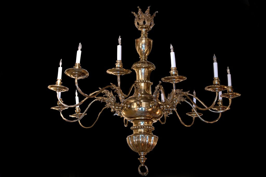 English brass chandelier having 12 lights. The floral canopy and turned stem issuing 12 scrolling arms terminating in bobeches and candleholders; marked 
