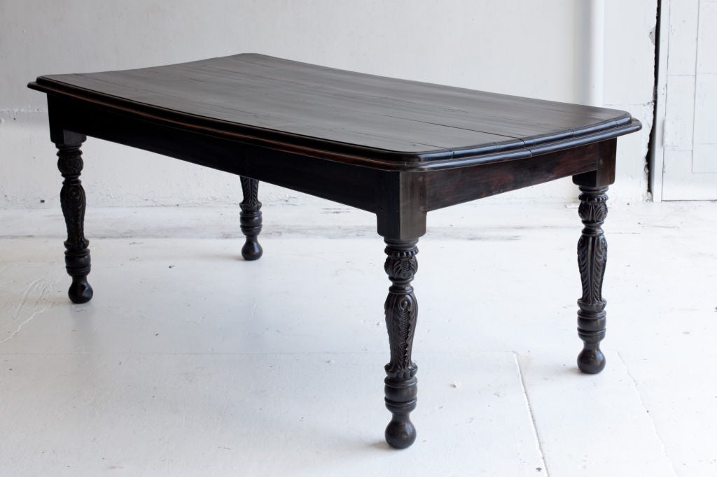 Very rare Anglo-Indian dining table or desk made from solid ebony. Top is made from 5 planks with rounded corners and large molded edge. Turned legs have floral carving.