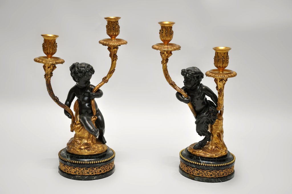 Pair of Rococo Patinated and Gilt Bronze Figural Candelabras. The left candelabra depicting the infant Dionysus (Greek god of wine and joy - Roman name Bacchus), crowned with ivy leaves and grapes. The right candelabra depicting an infant satyr