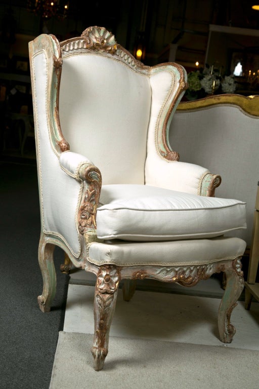 Pair of attractive and unique painted French bergere chairs in the style of Rococo, overall polychromed in distressed white and green (refer to the last photo for the exact finish), the elegantly carved frame with shell crest, downswept back, and