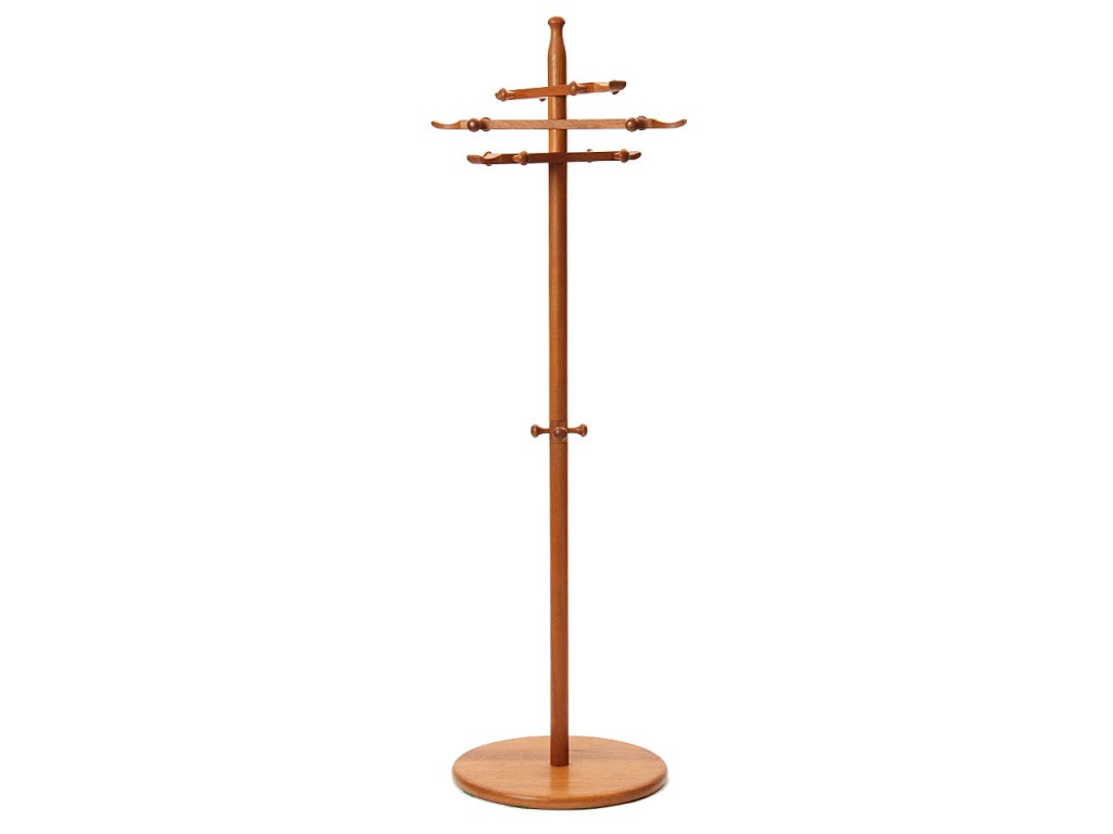 A well scaled, spare and finely crafted coat tree in solid teak having a disc base and vertical pole supporting three revolving arms with lathe turned hooks.