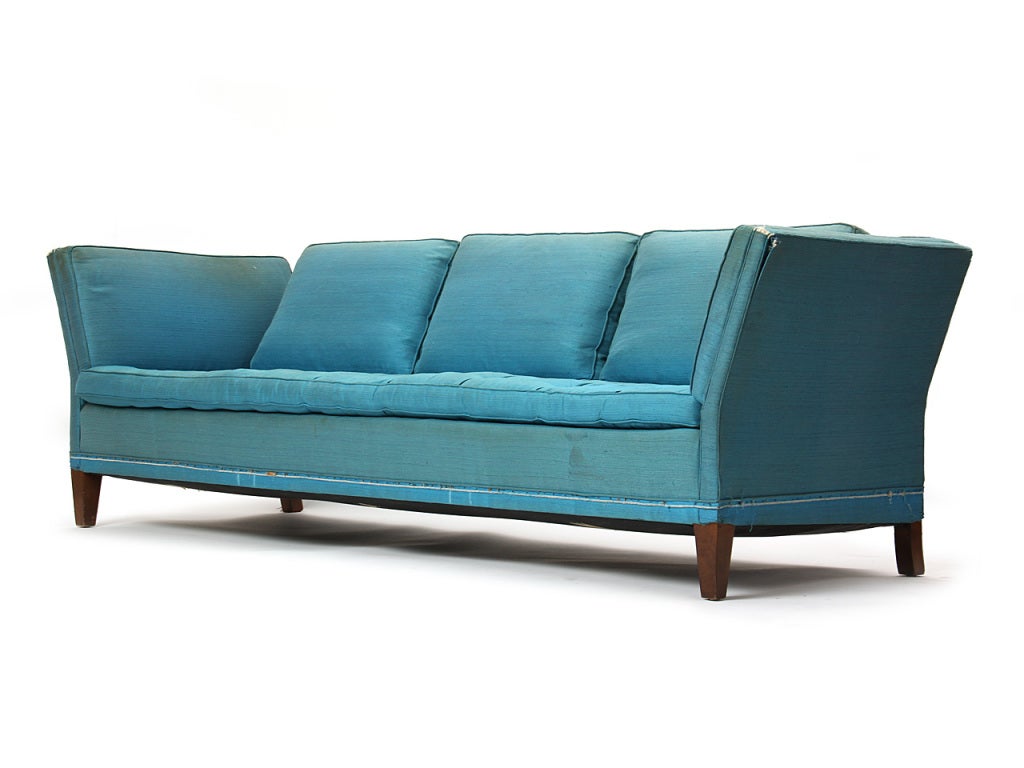 A dropped/ fixed open arm sofa on tapered legs and a tufted seat cushion. Seats three.