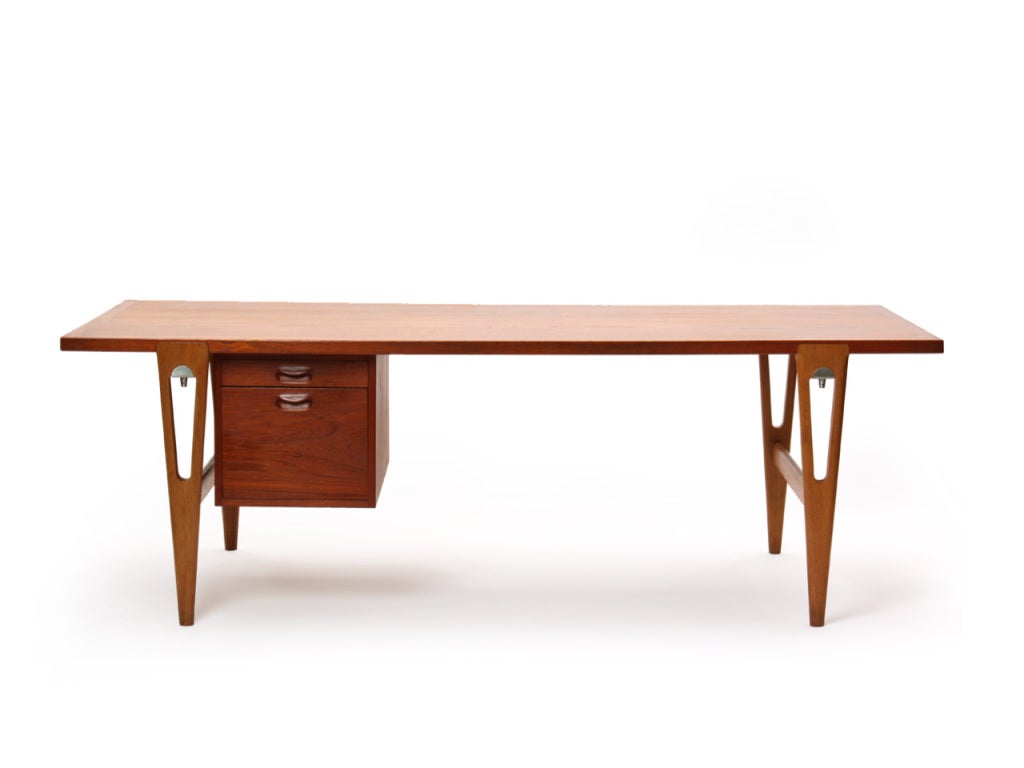 A rare desk with a teak top and two offset drawers with carved pulls (one file), on pierced, tapered oak legs with satin chrome connections.

Chair not included.