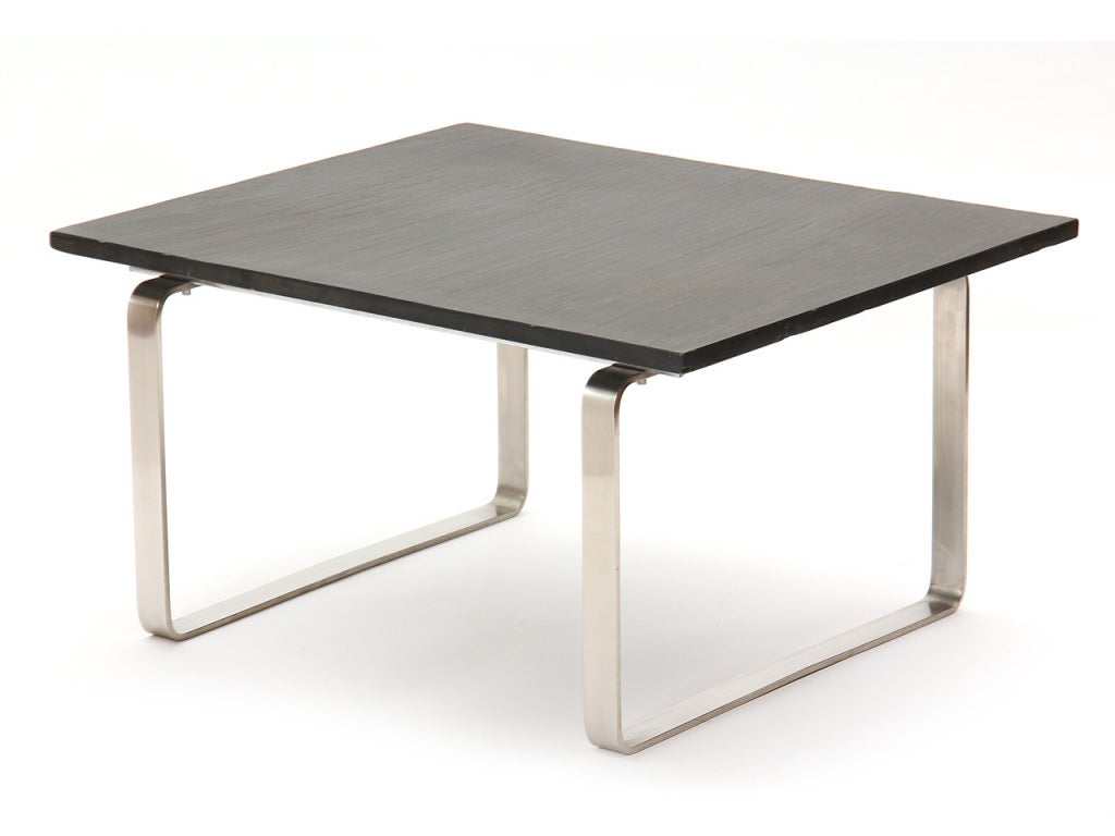 A low table with a rough hewn grey slate top on a base with brushed steel continuous flat-bar 