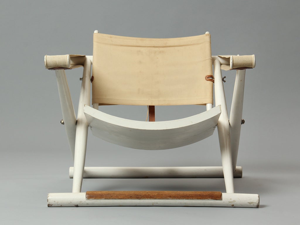 A scarce, early and finely detailed white-lacquered folding Egyptian or Safari chair having a distinctive curved seat, natural canvas back and armrests and an exposed oak footrest.