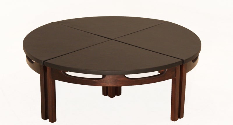A round sectional coffee table with supple black leather top and carved walnut base that can separate into four parts or be used as side tables. Each section measures 13