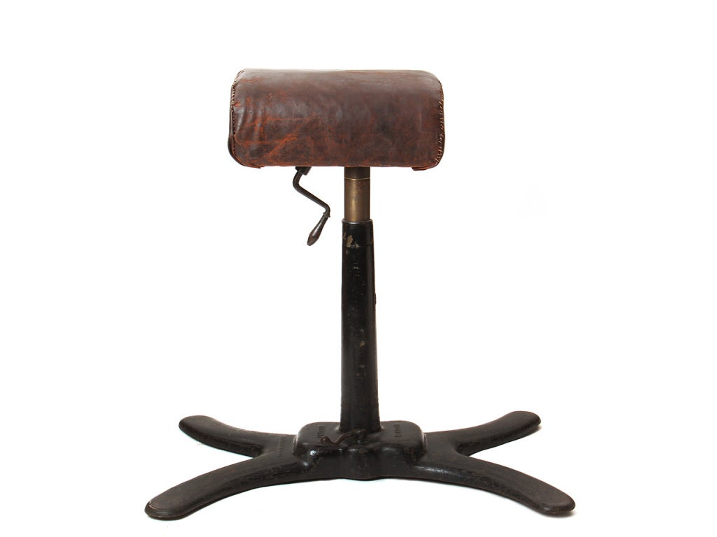 A gymnastics pommel horse or buck on a cast-iron base with locking / movable handle and geared height adjustment, retaining original leather.