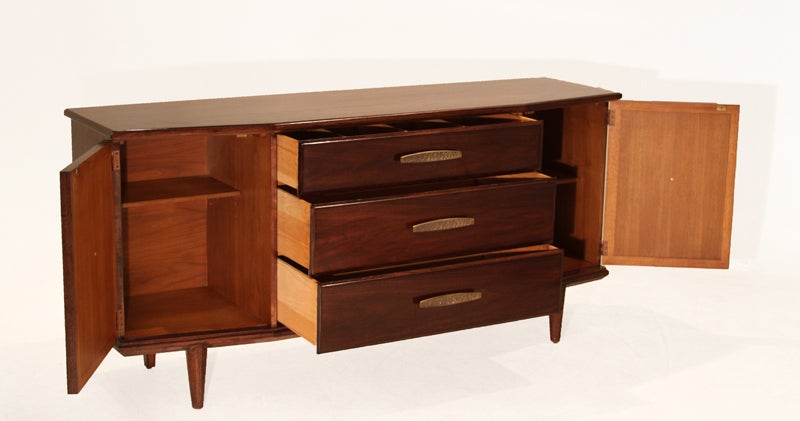 Beautiful angular Walnut buffet with original ornate bronze hardware and beautifully inset tan leather on the two doors flanking the 3 center drawers. The top drawer is lined with felt and is separated into sections, and the elegant angles of the
