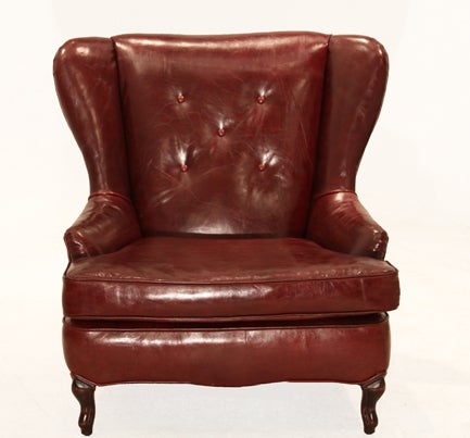 Slightly distressed oxblood leather and Walnut wing back chair with button tufted back and piping detail throughout. The base has cabriole legs in front and curved back legs.

Seat depth measures 22