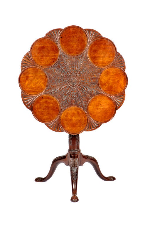 Georgianischer Mahagoni-Tisch mit Kippplatte. Das Oberteil ist mit gewölbten, durch Fächer getrennten Rondellen beschnitzt, die eine zentrale Rosette umgeben, aus der Akanthusblätter und Glockenblumen hervorgehen. Mit einem Vogelkäfig und einem