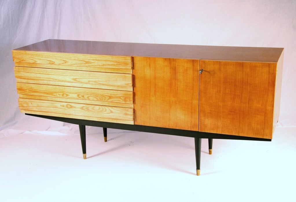 Italian maple credenza on black laquered legs terminating with brass sabots. The credenza is composed of 4 long drawers and two doors.