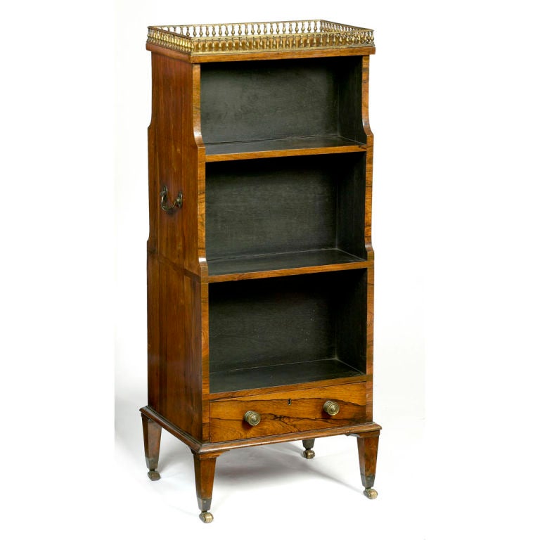 George III miniature double-sided waterfall bookcase with brass balustrade gallery top and single double-sided drawer below, raised on square section tapering legs and brass caps and castors.