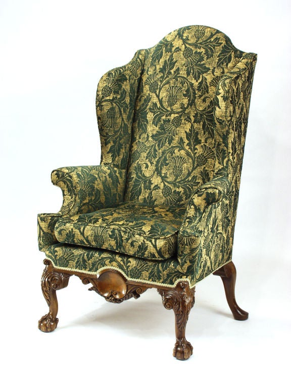 Georgian style mahogany wingback chair with a freize center of satinwood inlay shell. Cabriole legs headed by acanthus scrolls and ending on ball and claw feet.