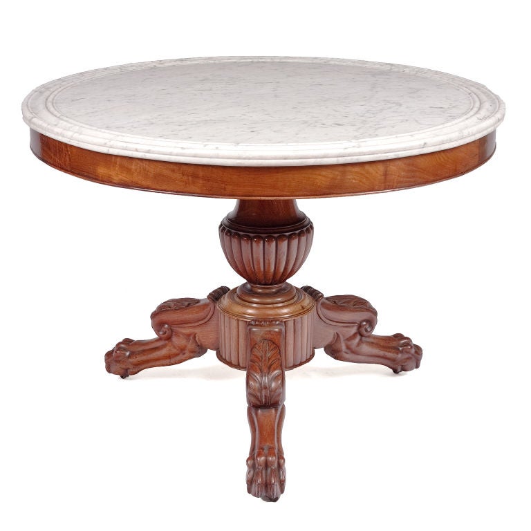 French mahogany center table with moulded marble top above plain frieze on vase-shaped reeded tripartite base with claw feet.
