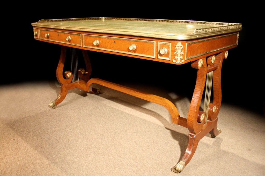 # E300 - Elegant Regency brass mounted writing table in the manner of John Mclean. Executed in Partridgewood, the mellow color and delicate graining is quite effective with the decorative brass detailing. The rectangular green leathered top with a