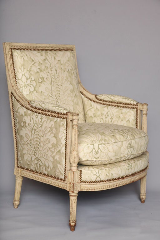 Pair of armchairs, in Directoire taste, distressed painted finish, each having square upholstered padded back with egg-and-dart carving, outswept padded arms with rosette-topped round fluted terminals, raised on round, tapering fluted legs. 