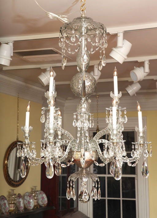 Georgian nine light cut glass chandelier having a shaped and faceted pendant canopy above a diamond-cut central ball with six upturned faceted arms having three lights and three spires, above six serpentine faceted arms with lights and cut and