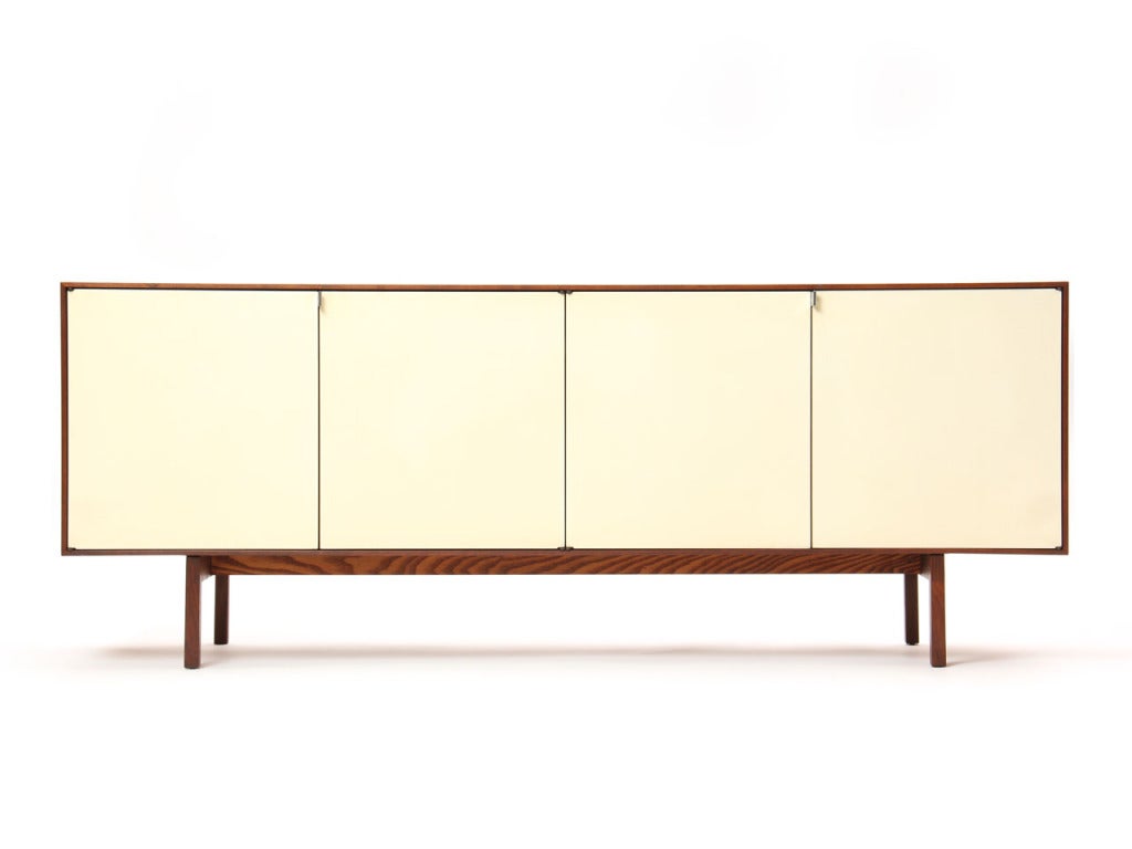 A four door walnut credenza with white lacquered doors revealing shelves and a pair of drawers.