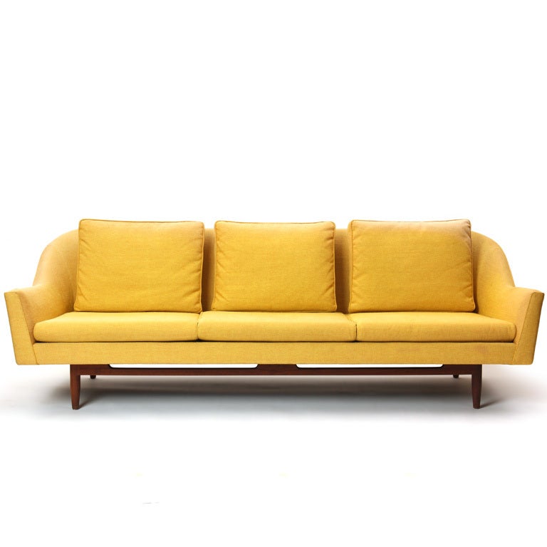 A three (3) seat sofa on a teak frame base retaining the original yellow upholstery.