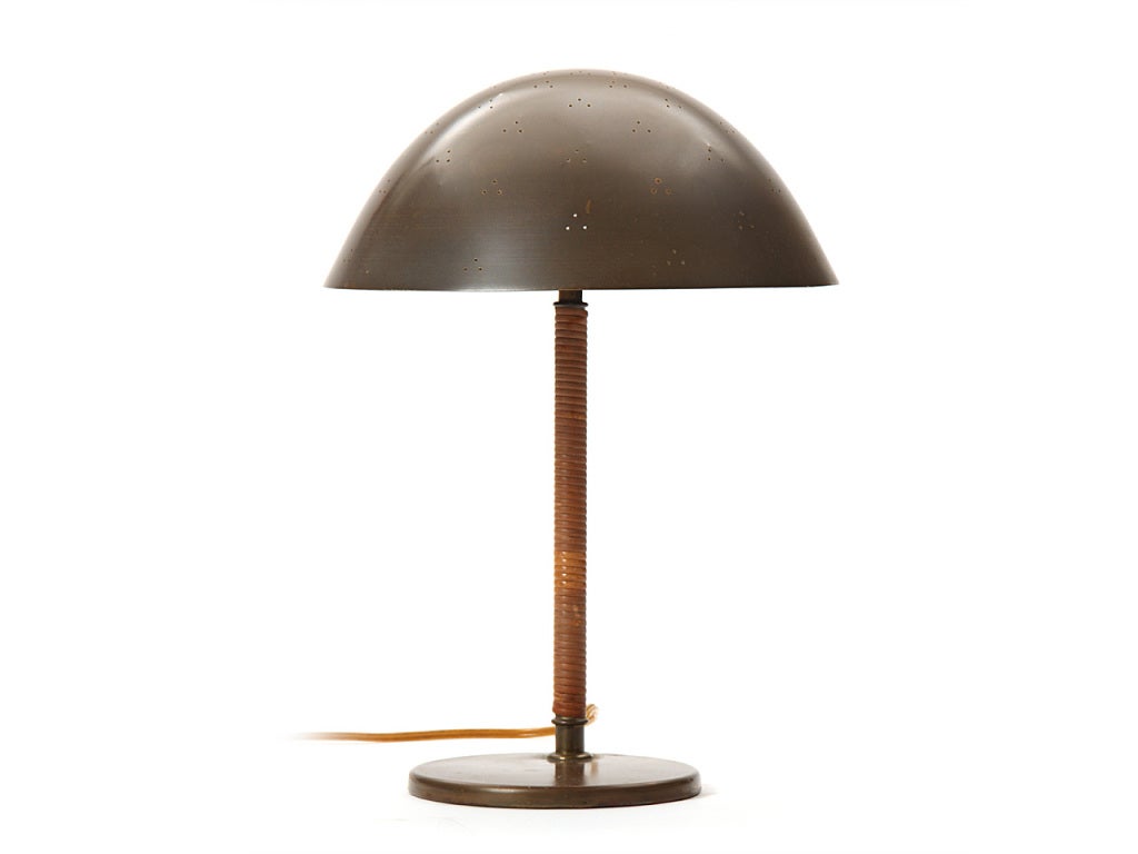 A brass desk lamp with an offset, cane-wrapped stem supporting a pinhole-perforated bowl shade, on a flat disc base.