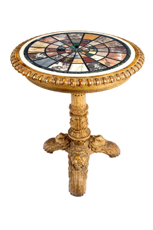 George IV giltwood and marble specimen table with concentric rings of specimen marbles on a turned shaft with leaf wrapped stem, on arched legs carved with lion's heads on paw feet.
