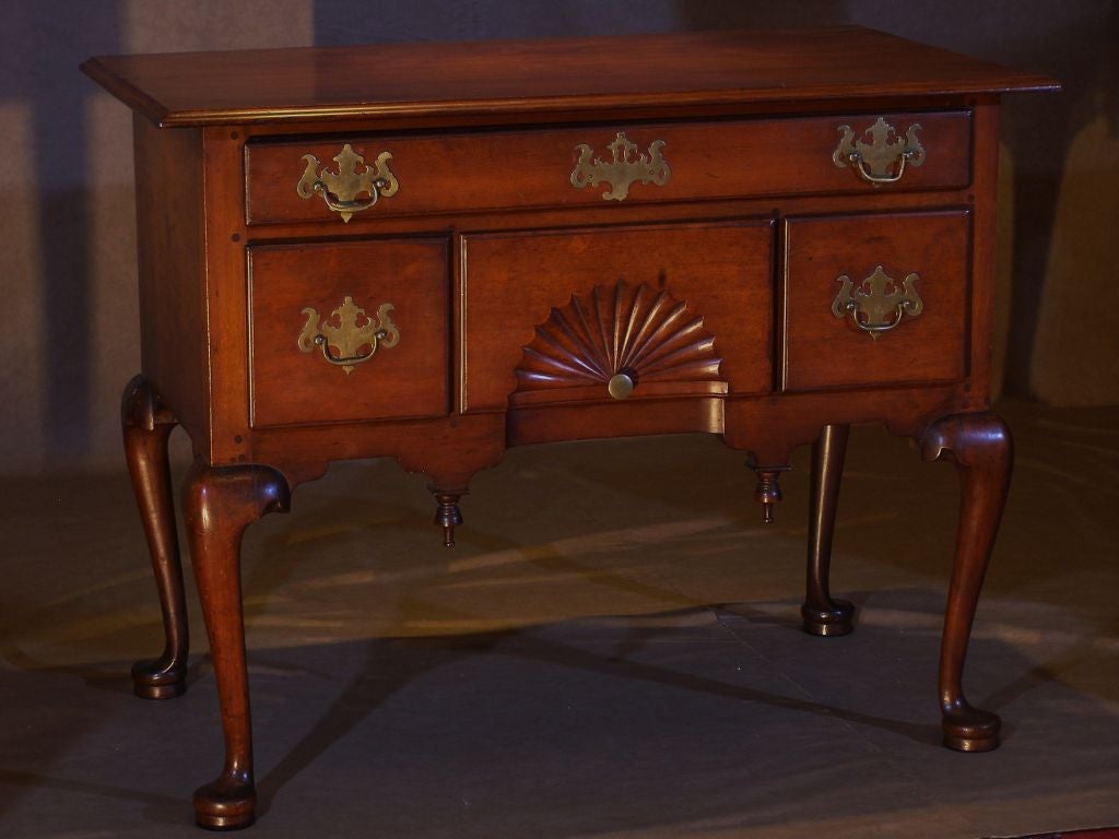 A fine example of a Massachusetts or Connecticut Cherry lowboy.  The overhanging top with a molded edge above a case with one long and three short drawers. The center drawer with a deeply carved fan. The whole on well formed cabriole legs ending in
