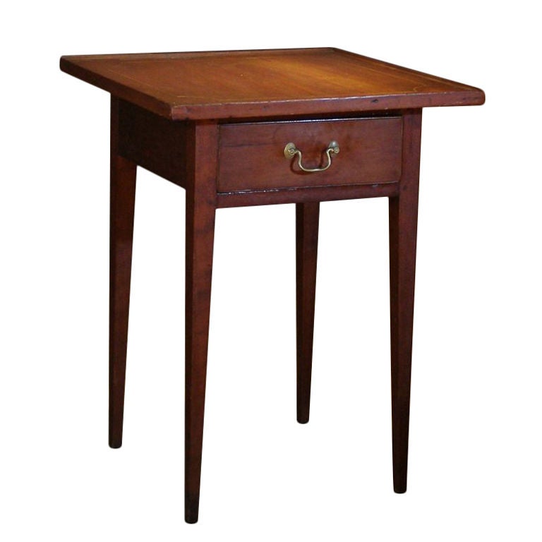 A good quality country New England cherry stand. The overhanging top has a bold line inlay and applied moldings on the edges. There is a deep drawer. The sharp taper of the square legs gives the table a good stance and the illusion the legs are