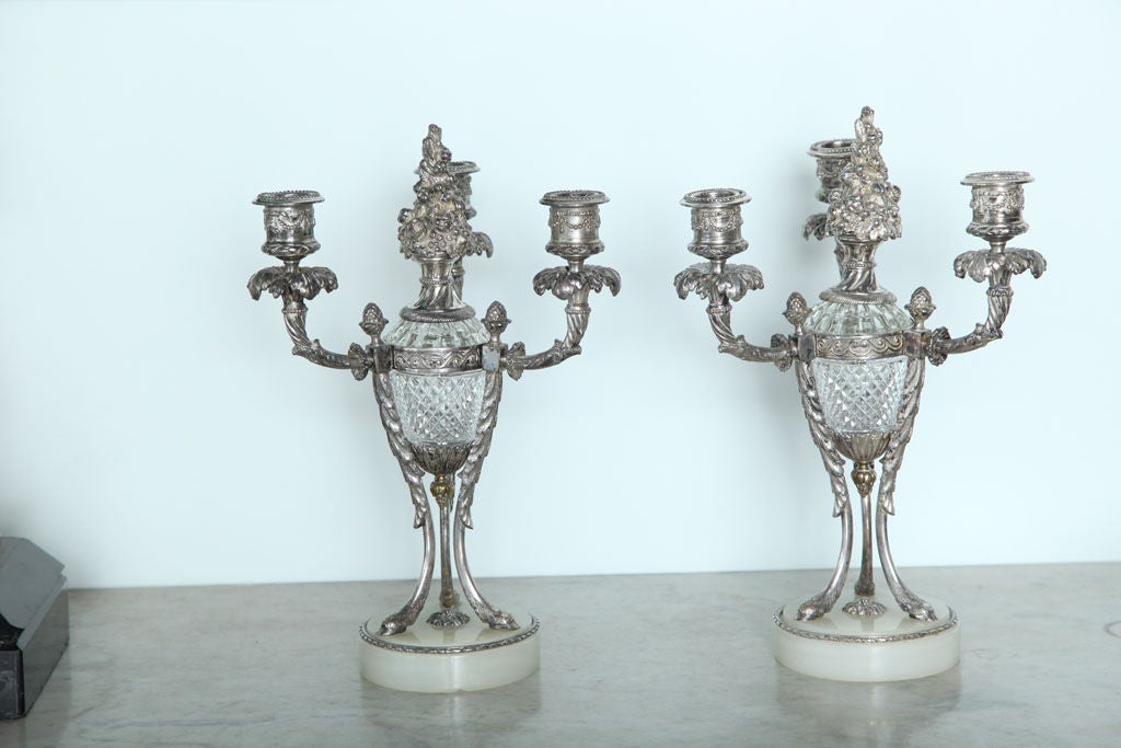 The three candle arms surrounding a floral motif atop a crystal center, resting on hoof foot supports, all above a marble base.
measures: base diameter 4.25