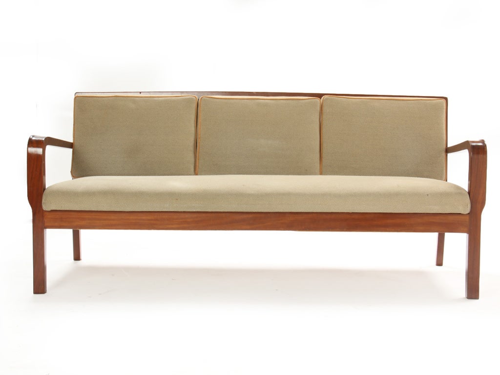 A slat-backed Cuban mahogany sofa with a tight seat and loose back cushions.