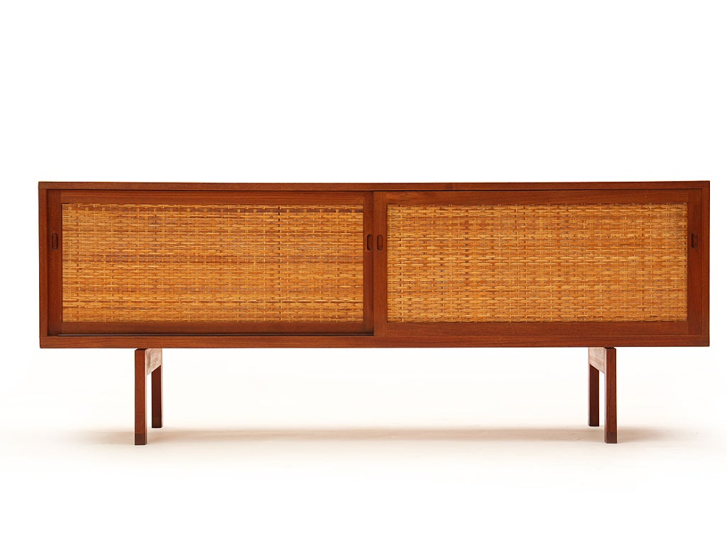 A teak credenza/cabinet/sideboard with caned inset sliding-door fronts. Manufactured by Ry Mobler. Storage portion is 19.5