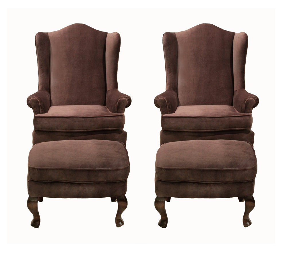 Comfortable pair of high back armchairs and ottomans upholstered in a dusky purple mohair with sculptural solid wood feet. The fabric has a sheen to it so that depending on the angle it makes the chairs sort of have a white shimmer. Please request a