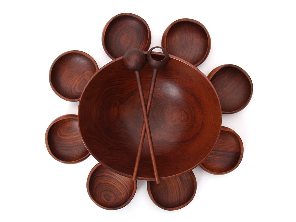 A large footed teak bowl with a bowed rim complemented by eight (8) hand turned teak salad bowls. Designed by Finn Juhl turned on a lathe by Magne Monsen for Kay Bojesen, Copenhagen Denmark