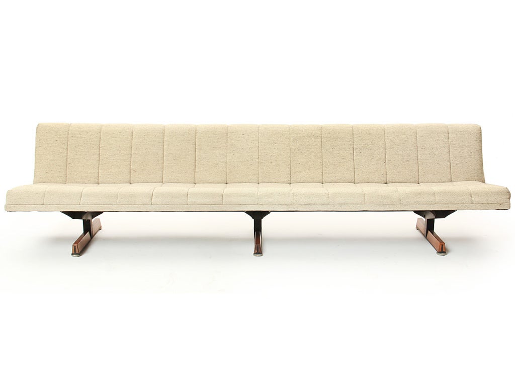 A long armless sofa on three solid walnut covered T-bar steel runner legs.