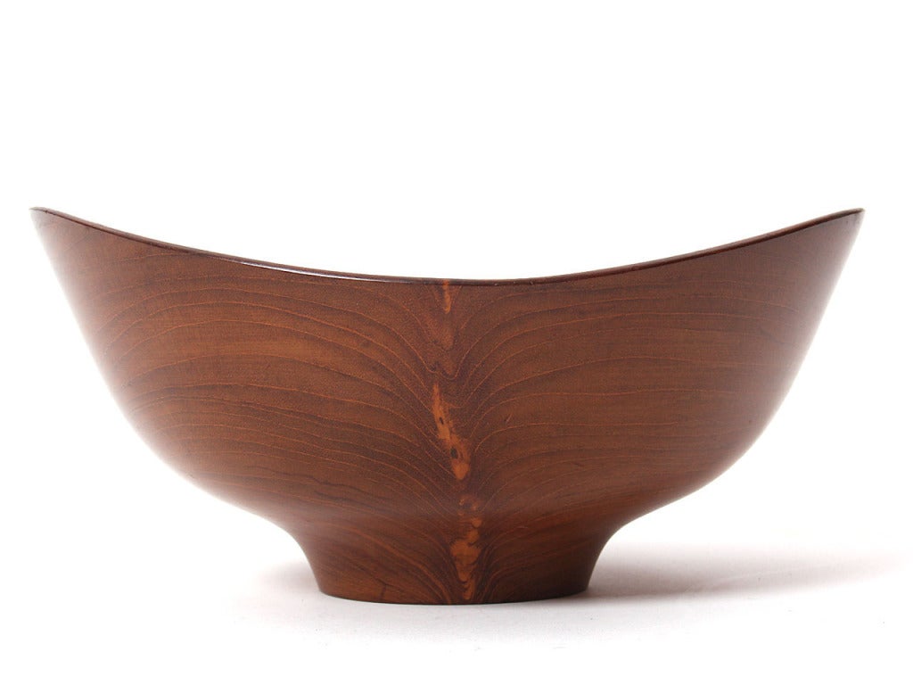 A medium sized hand turned footed teak bowl with a bowed rim. Designed by Finn Juhl and turned on a lathe by Magne Monson for Kay Bojesen.