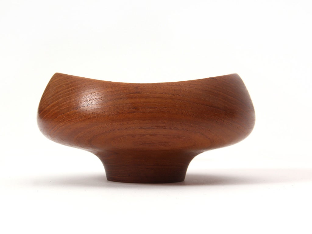 A small, footed turned teak bowl with a flat bottom.