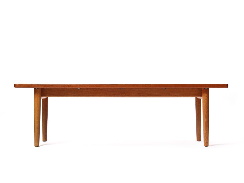 A rectangular solid teak top and oak base low table/bench/coffee table with a basin-edged top.
