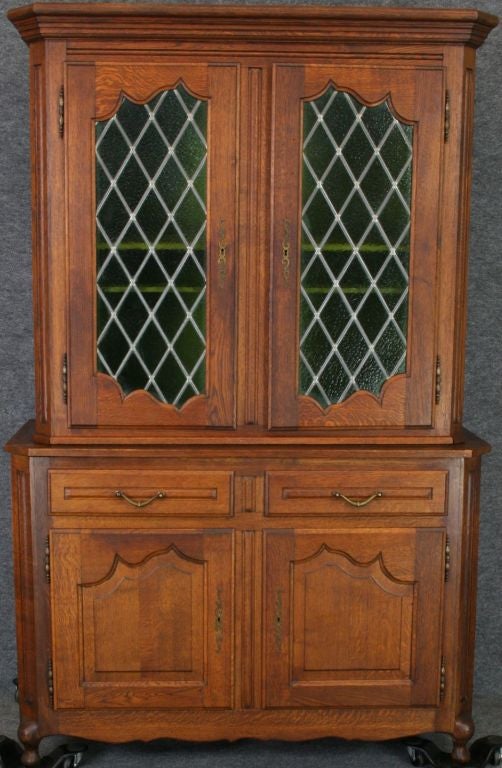 A French Country Bookcase China Cabinet Hutch in oak with two green leaded glass doors in upper cabinet and pretty cabriolet legs.