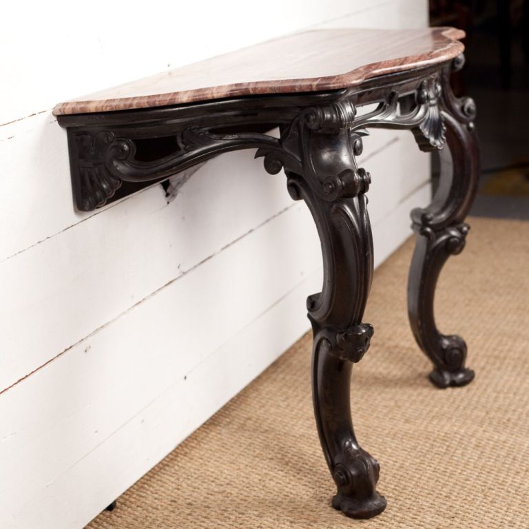 A pair of Anglo-Indian marble-topped console tables with carved mahogany bases. Beautifully figured marble tops. Tables must be mounted to the wall.