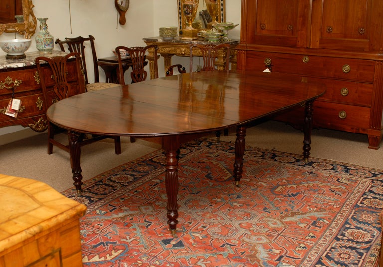 A  figured mahogany dining table with 2 leaves and turned reeded legs on brass castors. 

For many more fine antiques, please visit our online gallery at: www.williamwordantiques.com.

William Word Fine Antiques: Atlanta's source for antique