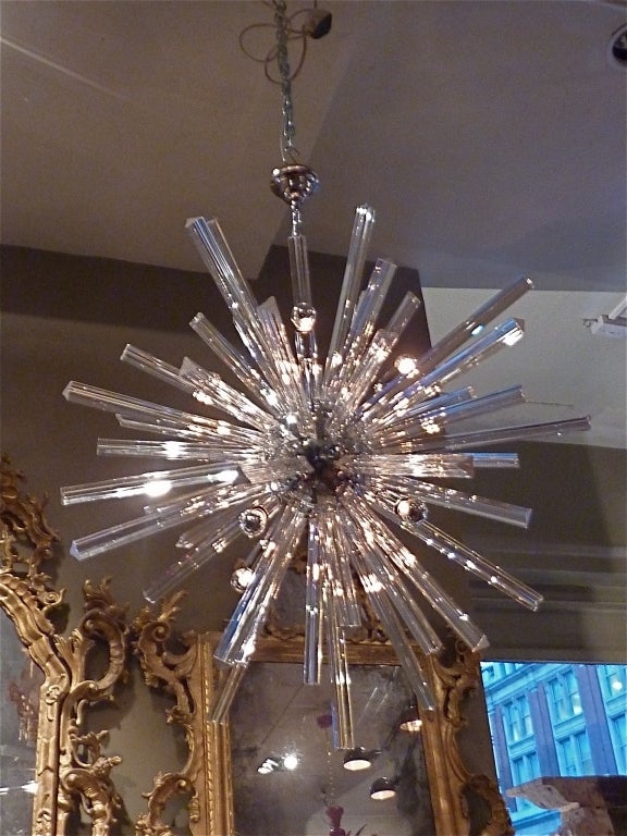 A fantastically radiant Italian mid-century modern Murano Glass Sputnik or Starbust Chandelier comprised of clear solid Murano glass rods, radiating from a chrome globe with nine sockets.  Each rod radiates and carries the light outward.  This