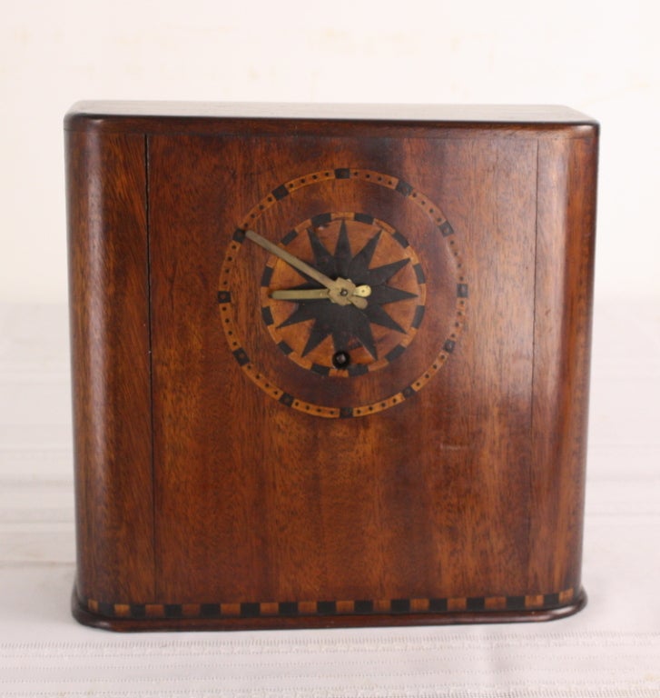 A very stylish Art Deco clock. Intricate marquetry along the top and bottom of the piece and around the clock face. Original brass key and interior works. Long running and quite accurate.