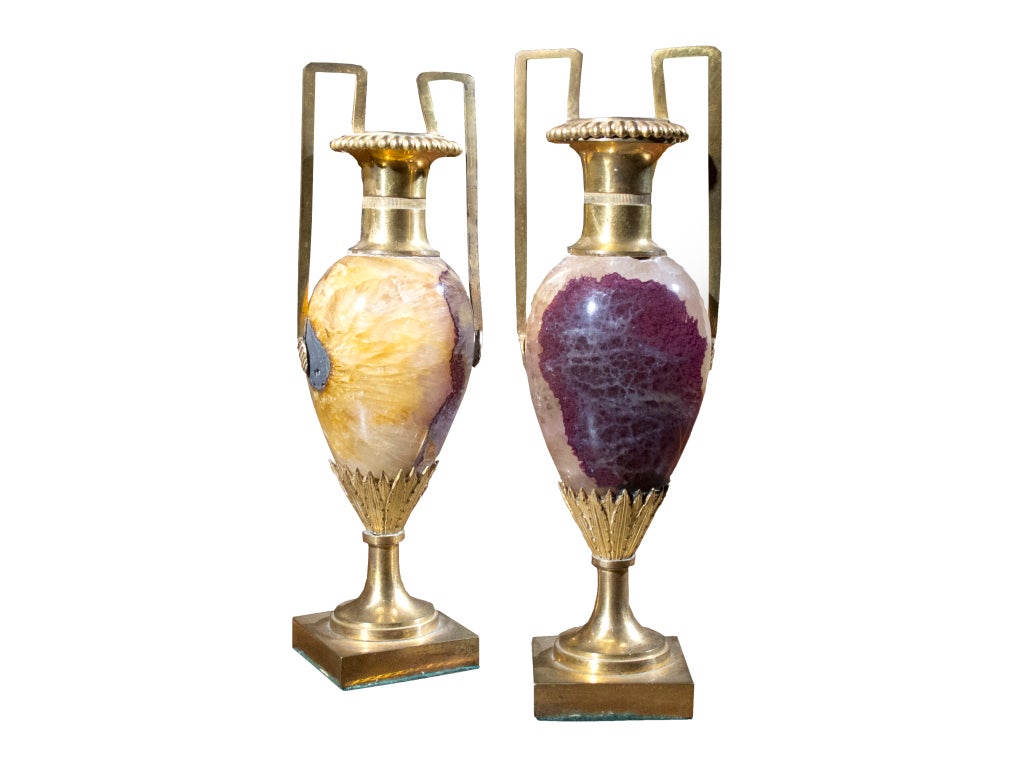 #W116
PAIR Blue John urns in the neoclassical style. The ovoid shaped body consists of well defined Blue John (Derbyshire Spar) having downswept graining. Ormulu mounted with decorative tops, flanked by a pair of handles and square plinth