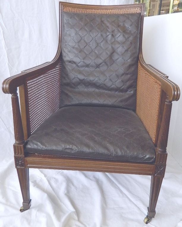 Antique English mahogany lounge or library chair on brass casters with patterned leather cushions and new French caning.