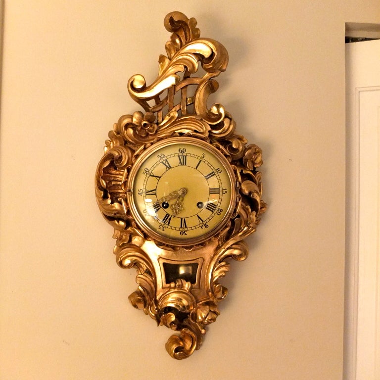 Swedish hand carved gilt-wood Rococo style, cartel clock,with chiming 14 day movement and flowing, curvilinear design. Marked on face: WESTERSTRAND - TÖREBODA. 

Clock works are spring driven, requiring winding every week. The pendulum is gilt