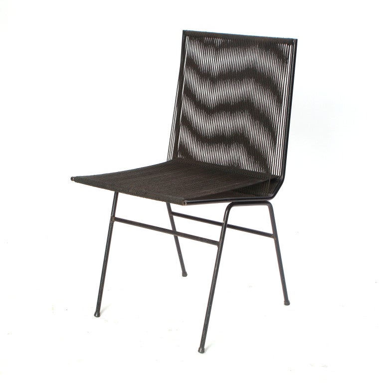 An indoor/outdoor occasional chair with a wrought iron frame and the original woven cord seat and back.