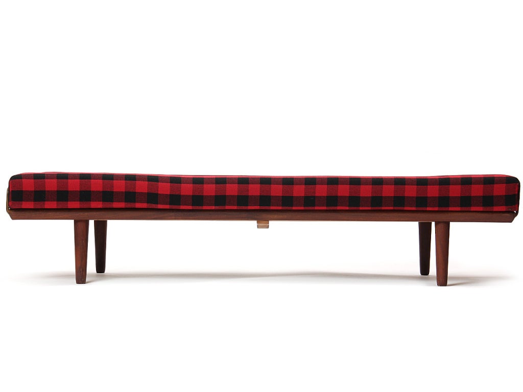 A teak daybed with brass rails to hold the cushion in original plaid wool upholstery.