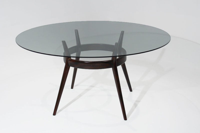 Round glass Rosewood dining table with four elegantly tapering legs that are, by design, slightly cinched inward by a conjoining band. Possibly by Giuseppi Scapinelli of Sao Paolo.

Many pieces are stored in our warehouse, so please click on