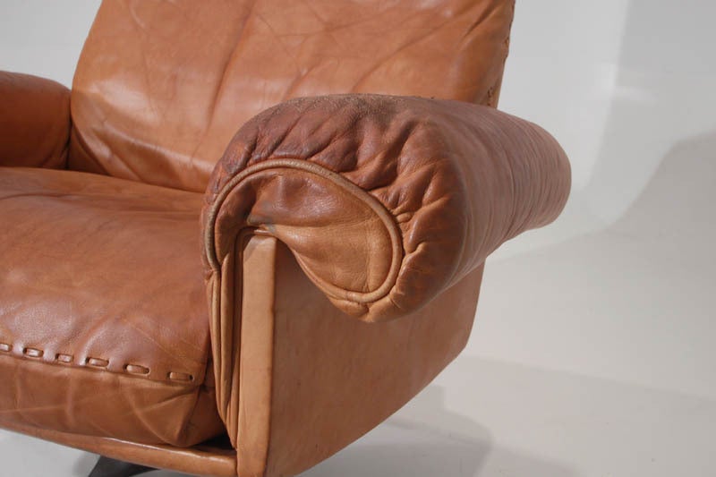 Swiveling caramel leather armchair and ottoman by De Sede 1